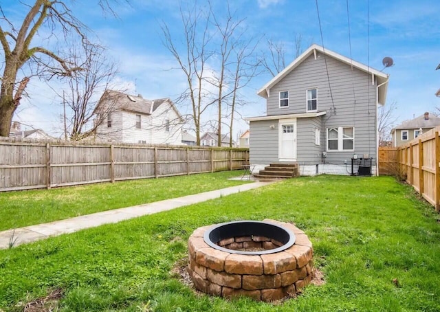 back of property with a yard, an outdoor fire pit, and central air condition unit