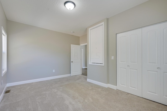 unfurnished bedroom featuring a closet, light colored carpet, and a textured ceiling