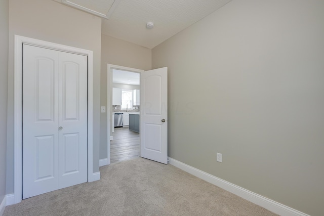 unfurnished bedroom with a closet, light colored carpet, and a textured ceiling