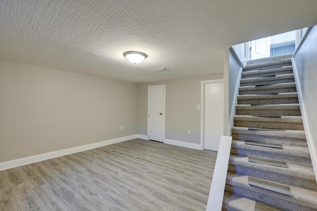 stairway featuring a textured ceiling and hardwood / wood-style flooring