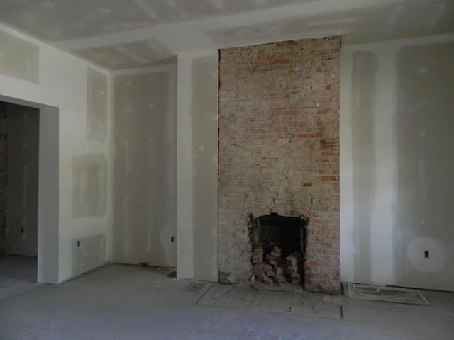 unfurnished living room with concrete flooring and a brick fireplace