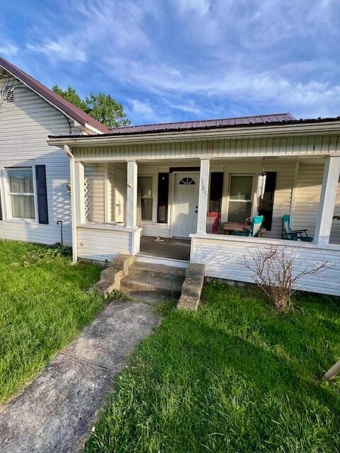 view of exterior entry with a porch and a yard