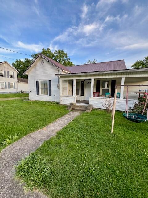 view of front facade with a front lawn, covered porch, and a carport