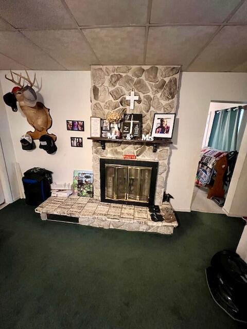 unfurnished living room with a fireplace, carpet floors, and a drop ceiling