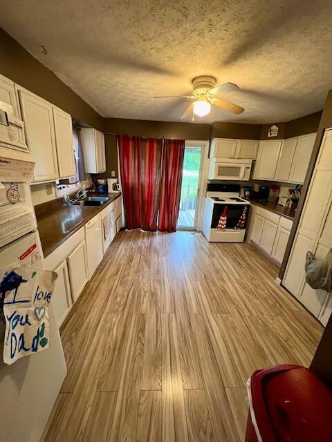 kitchen featuring a textured ceiling, white cabinetry, light hardwood / wood-style floors, and white appliances