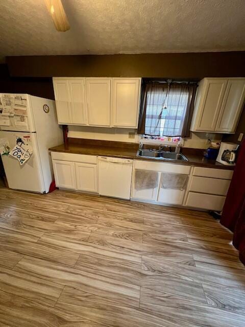 kitchen with a textured ceiling, white cabinets, white appliances, and sink