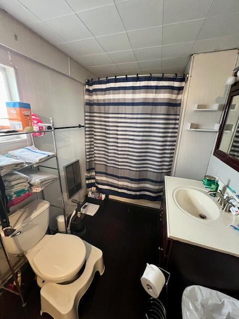 bathroom with walk in shower, a paneled ceiling, vanity, and toilet