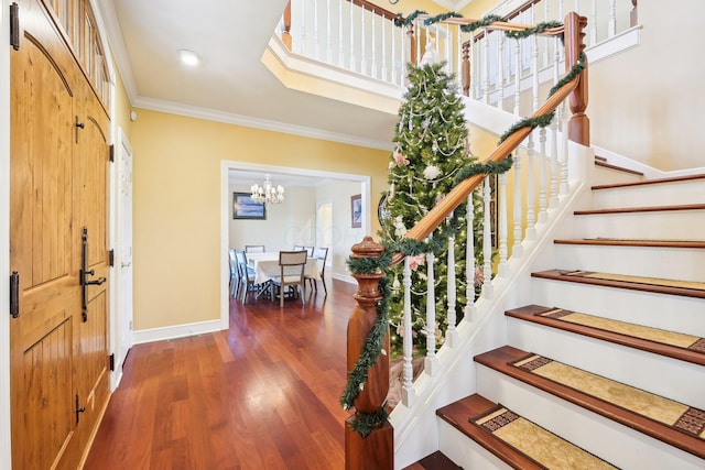 entrance foyer with dark hardwood / wood-style floors, crown molding, and a notable chandelier