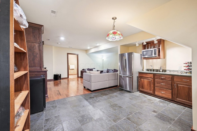 kitchen featuring appliances with stainless steel finishes, decorative light fixtures, dark wood-type flooring, and sink