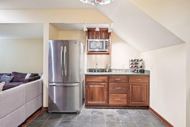 kitchen with appliances with stainless steel finishes, track lighting, vaulted ceiling, and sink