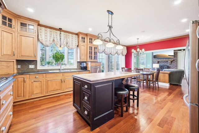 kitchen featuring a center island, hanging light fixtures, hardwood / wood-style flooring, tasteful backsplash, and a kitchen bar