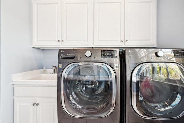 laundry area with cabinets, washing machine and dryer, and sink