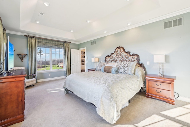 carpeted bedroom with ornamental molding and a tray ceiling