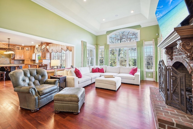 living room with a tray ceiling, a chandelier, a fireplace, a high ceiling, and dark hardwood / wood-style floors