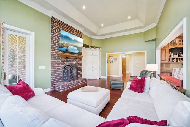 living room featuring a raised ceiling, a fireplace, dark wood-type flooring, and ornamental molding