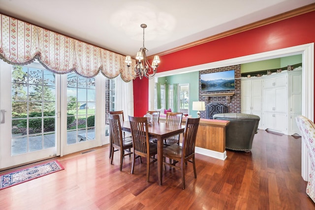 dining space with dark hardwood / wood-style floors, a healthy amount of sunlight, a fireplace, and an inviting chandelier