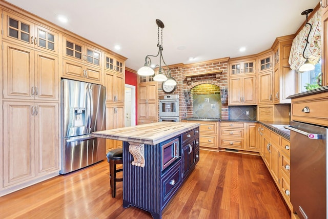 kitchen featuring wood counters, appliances with stainless steel finishes, a breakfast bar, hardwood / wood-style flooring, and a kitchen island