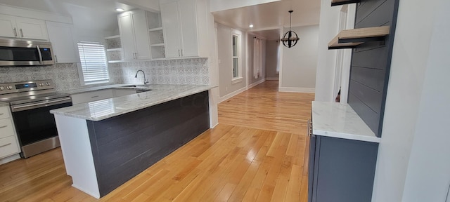 kitchen featuring light stone countertops, stainless steel appliances, white cabinetry, and light hardwood / wood-style floors