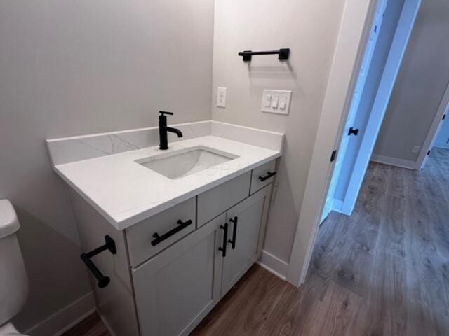 bathroom with hardwood / wood-style flooring, vanity, and toilet