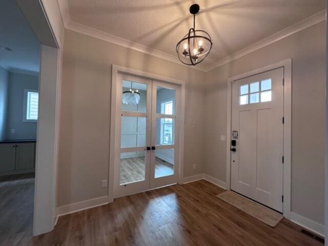 foyer featuring a notable chandelier, dark hardwood / wood-style flooring, a wealth of natural light, and french doors