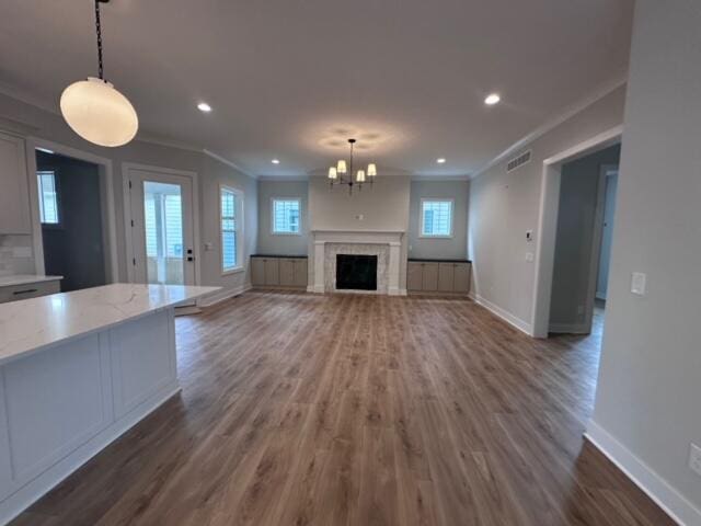 unfurnished living room featuring a tile fireplace, dark hardwood / wood-style floors, a chandelier, and crown molding