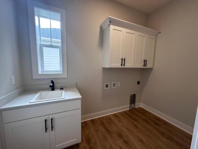 washroom with electric dryer hookup, cabinets, dark wood-type flooring, sink, and washer hookup