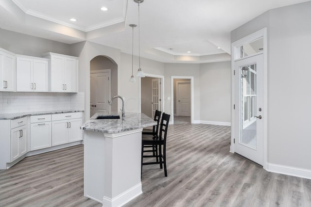 kitchen featuring white cabinets, a center island with sink, light hardwood / wood-style flooring, and sink