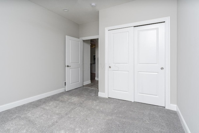 unfurnished bedroom featuring light carpet and a closet