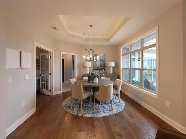 dining space featuring a chandelier, dark hardwood / wood-style floors, and a tray ceiling