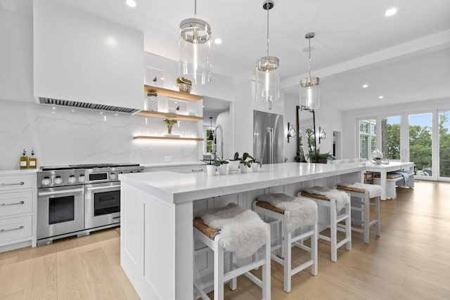 kitchen with decorative backsplash, white cabinetry, pendant lighting, and premium appliances