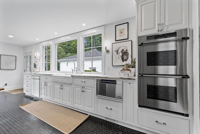 kitchen featuring white cabinetry, stainless steel double oven, and sink