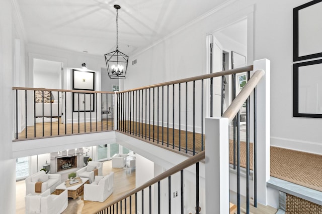 stairs featuring hardwood / wood-style floors, ornamental molding, and a chandelier