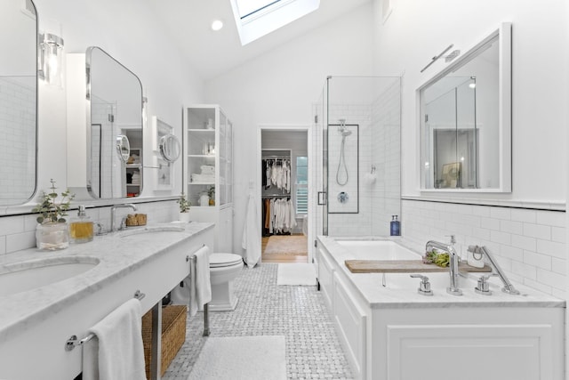 full bathroom featuring a skylight, tile patterned flooring, shower with separate bathtub, toilet, and vanity