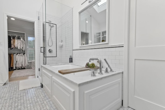 bathroom featuring tasteful backsplash, a skylight, and an enclosed shower