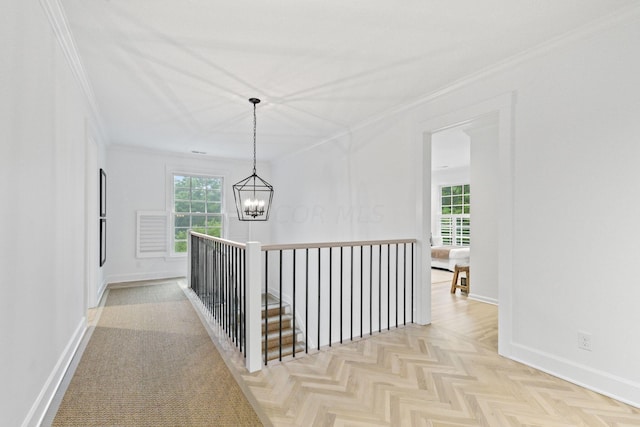 hall featuring crown molding, light parquet floors, and an inviting chandelier