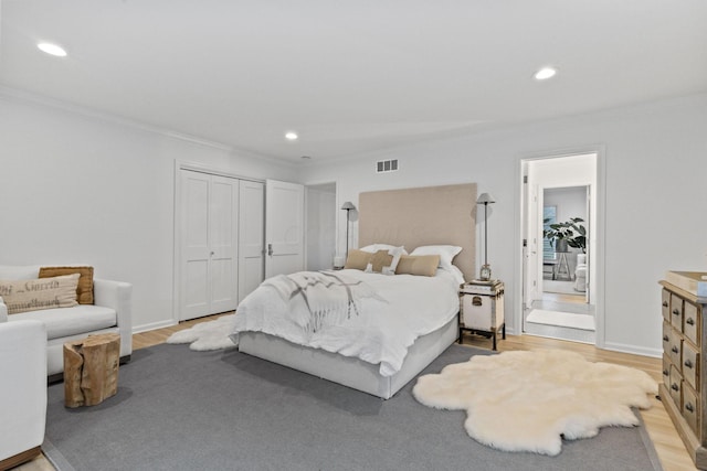 bedroom with a closet, ornamental molding, and light wood-type flooring