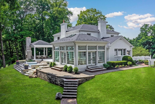 rear view of property with a patio, a lawn, and a sunroom