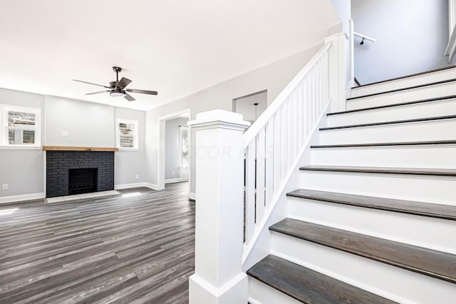 stairway featuring ceiling fan, a fireplace, and hardwood / wood-style flooring