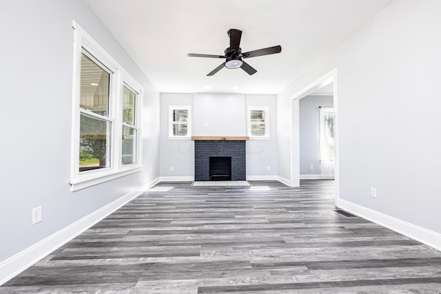 unfurnished living room with hardwood / wood-style flooring, a brick fireplace, and ceiling fan