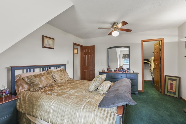 bedroom with ceiling fan, dark carpet, a walk in closet, and a closet