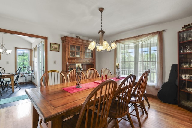 dining room featuring dark hardwood / wood-style floors, vaulted ceiling, and a chandelier