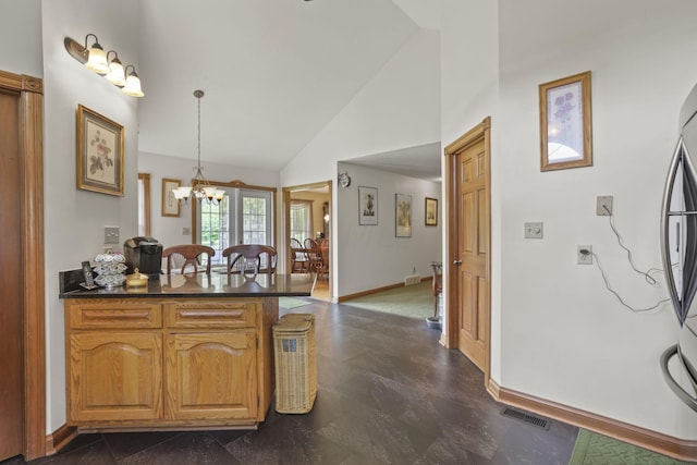 kitchen with stainless steel refrigerator, hanging light fixtures, high vaulted ceiling, a notable chandelier, and kitchen peninsula