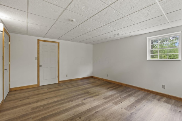 unfurnished room with a drop ceiling and wood-type flooring