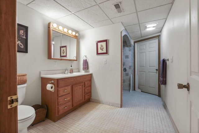 bathroom featuring tile patterned floors, a drop ceiling, vanity, and toilet