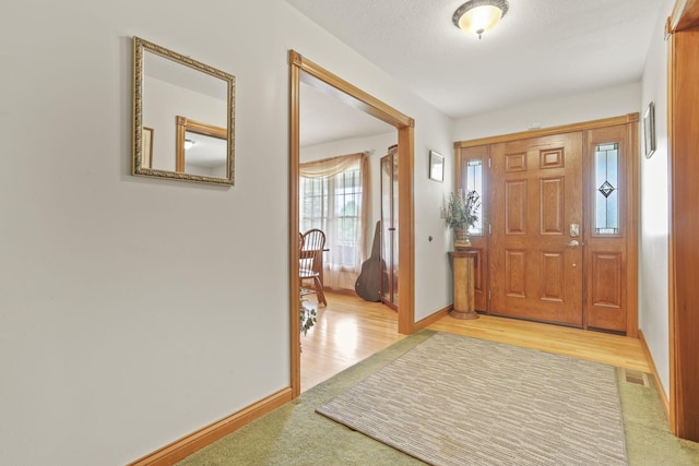 foyer with a textured ceiling and light hardwood / wood-style flooring