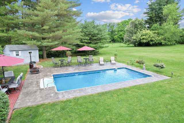 view of pool featuring a yard, an outdoor structure, and an outdoor fire pit