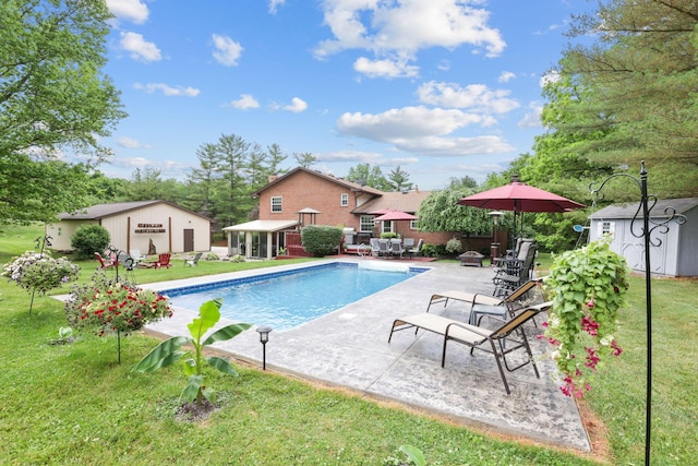 view of pool featuring a yard, a patio, and a storage unit