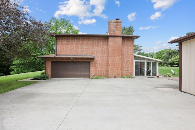 view of side of property with a sunroom, a garage, and a yard