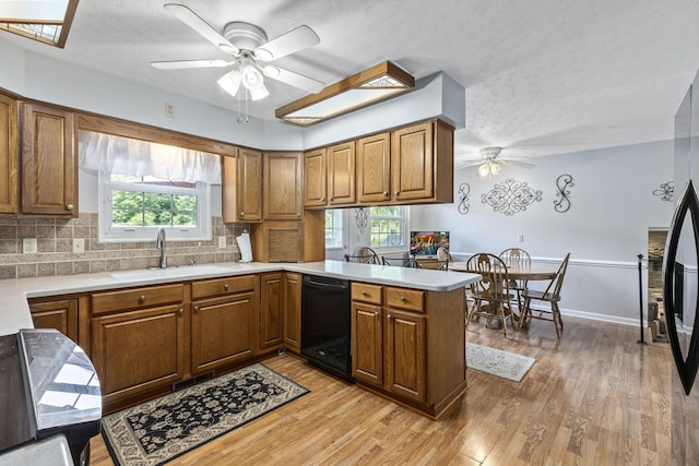 kitchen with kitchen peninsula, a wealth of natural light, sink, and black dishwasher