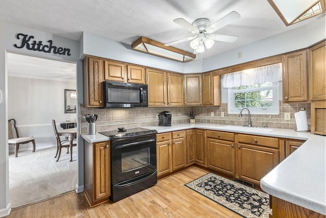 kitchen with sink, backsplash, light hardwood / wood-style flooring, and black appliances